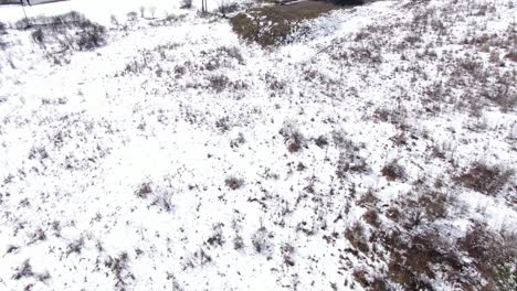 Aerial-Drone-Footage-Pushing-Forward-and-Panning-Up-to-Reveal-a-White,-Old-House-on-the-Edge-of-the-Snow-Covered-Forest