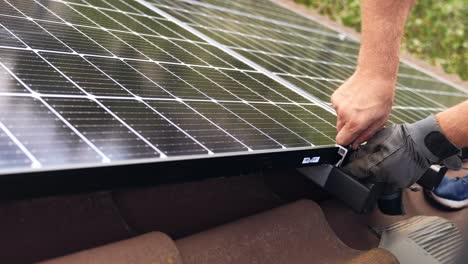 Engineer-fixing-solar-panel-cells-on-rooftop-with-his-hands,-close-up-view