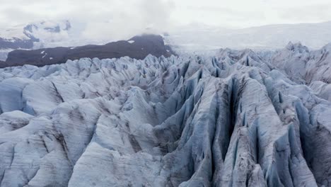 Fjallsárlón-ice-glacier-with-rough-jagged-surface-in-Iceland-on-cloudy-day,-aerial
