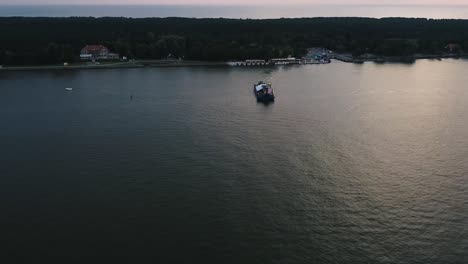 Cinematic-aerial-drone-shot-of-a-ferry-moving-across-the-river-with-a-lot-of-people-traveling-across-1