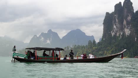A-longtail-boat-is-sailing-in-Khao-Sok-National-Park-in-Thailand-with-huge-and-beautiful-rock-formations-in-the-background-on-a-cloudy-day
