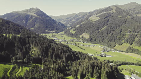 Aerial-over-picturesque-tyrolean-countryside-with-forest-covered-mountains-and-grassy-fields