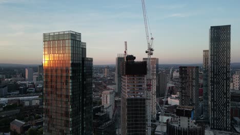 Aerial-drone-flight-in-Manchester-around-Deansgate-Towers-and-new-construction-of-high-rises-with-the-sunset-in-the-reflection-of-the-glass