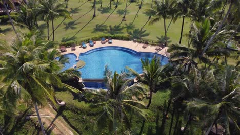 Schöner-Und-Tropischer-Pool-Mit-Der-Sonne,-Die-Sich-Im-Wasser-Widerspiegelt,-Umgeben-Von-Palmen-Und-Einigen-Charmanten-Bungalows-Im-Hintergrund,-An-Einem-Klaren-Blauen-Tag-Auf-Der-Insel-Koh-Kood-In-Thailand---Asien
