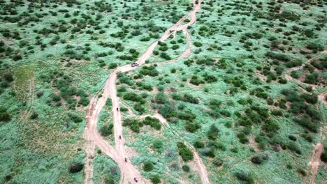 Safari-Caravan-With-Motorcycles-And-Jeep-Traveling-Through-Kenyan-Landscape---aerial-panoramic