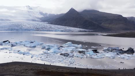 Menschen,-Die-Am-Lagunenufer-In-Der-Arktischen-Landschaft-Stehen-Und-Auf-Gekalbte-Eisberge-Blicken