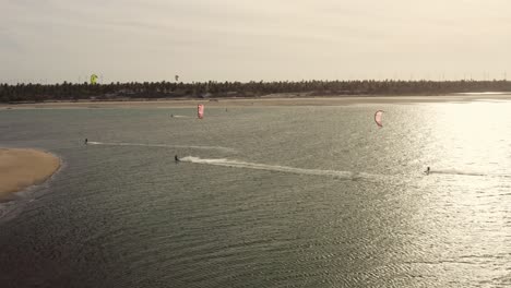 Drei-Kite-Surfer,-Die-Im-Abendrot-In-Meereskräuselung-Segeln