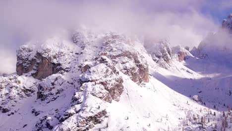 Grand-high-cliffs-of-Alpine-mountain-range-during-white-snow-winter-covered-in-clouds