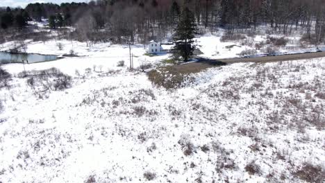 Aerial-Drone-Footage-Pulling-Away-from-an-Old,-White-House-to-Reveal-the-Snow-Covered-Countryside-and-Forest