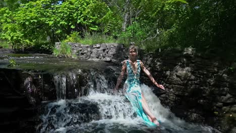 Young-women-sitting-on-a-small-waterfall-in-a-swimsuit-on-a-summer-day-slow-motion-panning-shot