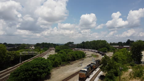 Arial-front-shot-of-a-train-going-by-during-a-warm-summer-day-with-many-visible-clouds