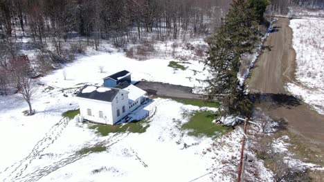 Luftaufnahmen-Von-Drohnen,-Die-Direkt-Um-Ein-Altes,-Weißes-Haus-Am-Rande-Eines-Schneebedeckten-Waldes-Kreisen
