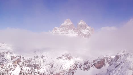 Flying-through-clouds-revealing-majestic-tall-rock-peaks-in-Italian-Dolomites,-aerial
