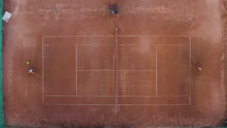 Tennis-players-at-clay-court,-hitting-net,-zooming-overhead-shot