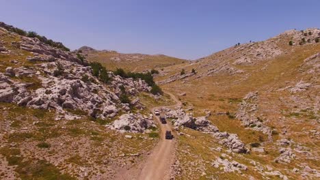 Off-road-cars-driving-on-mountain-and-rocks,-dry-land