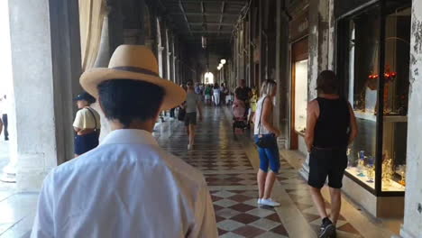 Venice,-Man-walking-with-a-hat-under-San-Marco-Square-arcade,-cinematographic,-daytime,-6-seconds,-HD,-30-frames-per-second