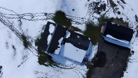 Luftaufnahmen-Von-Drohnen,-Die-über-Einem-Schneebedeckten-Haus-Am-Waldrand-Aufsteigen-Und-Sich-Winden