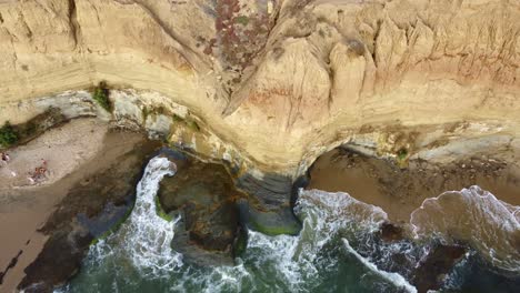 Aerial-top-down,-gentle-waves-crashing-onto-coastal-sea-cliffs-in-Sunset-Cliffs,-San-Diego