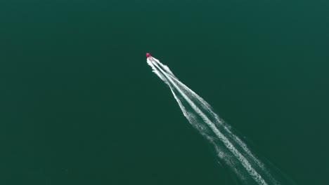 Overhead-aerial-view-of-a-red-motorboat-ripping-through-the-frame