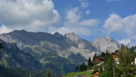 Zeitraffer-Der-Schweizer-Felsberge-In-Den-Alpen,-Obwalden-Und-Der-Bewölkte-Himmel,-Kleines-Dorf-Rechts