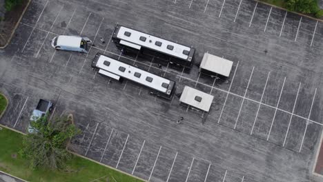 Aerial-view-towards-two-tour-buses-parked-on-a-parking-lot---tilt,-drone-shot