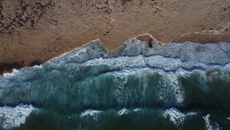 Waves-hitting-beach,-top-down-drone-view-of-relaxing-ocean-coast-background