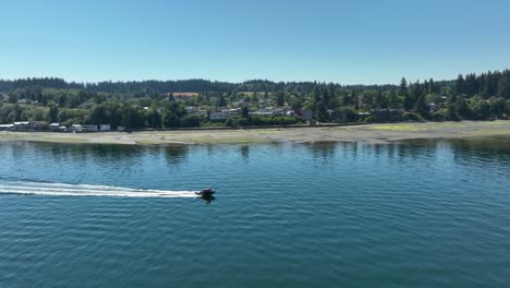 Aerial-shot-of-a-motorboat-passing-by-the-city-of-Langley-on-Whidbey-Island