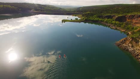 Gente-Haciendo-Kayak-En-El-Río,-Naturaleza-Verde-Y-Cielo-Lleno-De-Nubes
