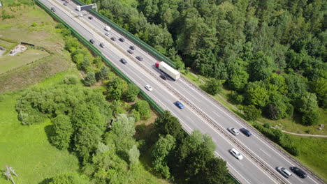 Aerial-top-down-shot-of-traffic-and-traffic-jam-on-rural-highway-surrounded-by-forest-and-fields-at-sun