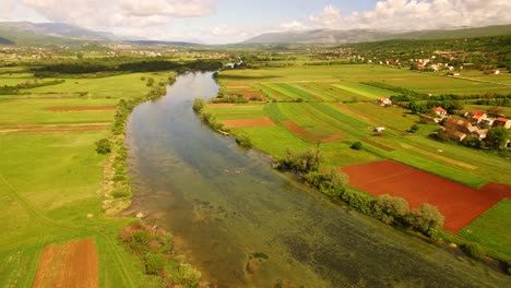 Drone-over-river,-green-nature-and-sky-full-of-clouds-1
