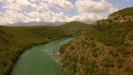Drone-over-river,-green-nature-and-sky-full-of-clouds