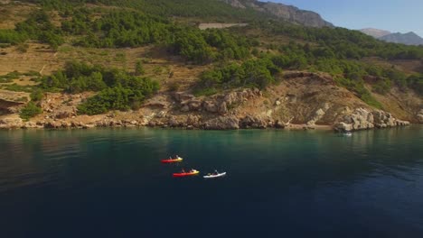 Gente-Haciendo-Kayak-En-El-Mar,-Naturaleza-Verde-Y-Rocas