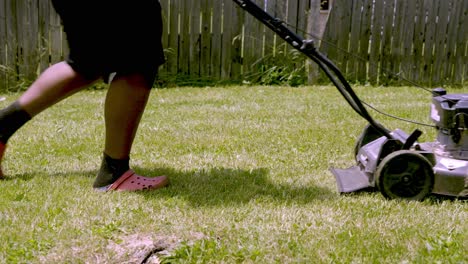 Low-angle-view,-African-American-male-with-lawn-mower-on-green-grass-in-the-garden,-Slow-motion