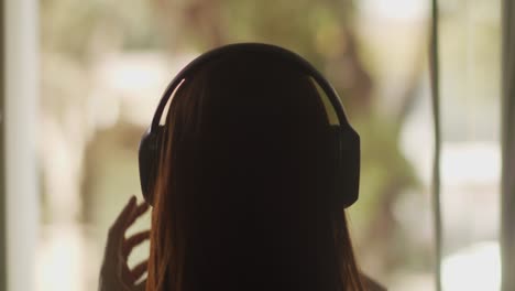 Static-shot,-back-of-girl's-head-putting-on-wireless-headphones