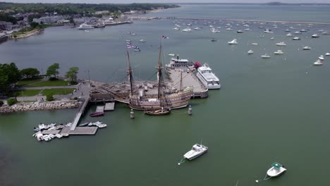 Aerial-view-away-from-the-Mayflower-II-schooner-docked-in-Plymouth,-USA---pull-back,-tilt,-drone-shot