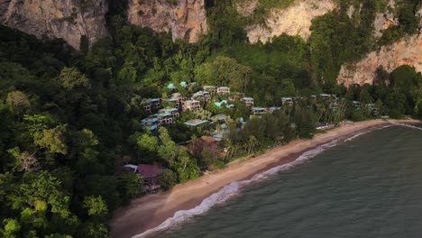 Aerial-drone-forward-moving-shot-of-beautiful-resort-surrounded-by-tropical-forest-along-Raily-beach-in-Krabi,-Thailand-at-daytime