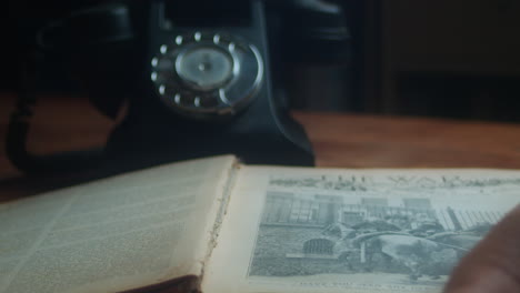 Vintage-Styled-Scene-of-Someone-Opening-Pages-of-a-Book-While-Answering-an-Old-Telephone-on-the-Desk