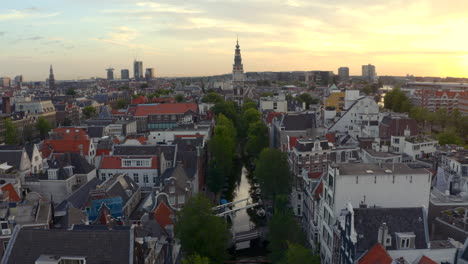 Slow-cinematic-drone-shot-over-small-Amsterdam-canal-towards-Zuiderkerk-Church