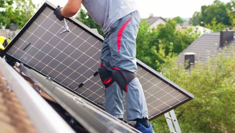 Unrecognizable-Roofer-carrying-Solar-Panel-to-install-on-top-of-roof,-day