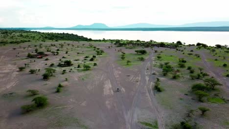 Traveler-Riding-Motorcycle-Through-Idyllic-Landscape-Of-Lake-Magadi-In-Kenya---aerial-pullback