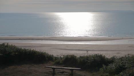Lone-Bench-Woolacombe-Panning-Up-Shot-Showing-Sun-Reflection-on-Calm-Sea