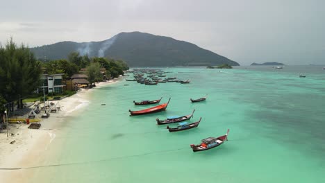 Low-flyover-shot-of-a-boat-filled-beach-on-Ko-Lipe-Island,-Thailand