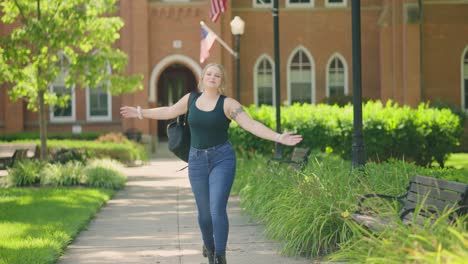 Girl-wearing-backpack-jumps-for-joy-and-celebrates-in-front-of-a-college-university