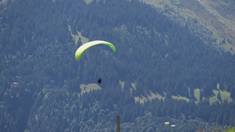A-parachute-twirls-while-descending-in-the-plain-of-Engelberg,-Obwalden-in-the-Swiss-alps