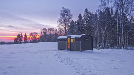 Timelapse-shot-of-people-walking-around-a-wooden-cabin-surrounded-by-cold-winter-landscape-at-dawn
