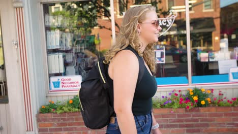 Girl-walks-down-sidewalk-while-wearing-sunglasses