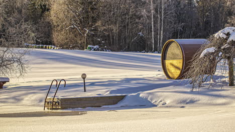Beautiful-timelapse-shot-of-wooden-barrel-sauna-beside-a-frozen-white-lake-during-winter-time