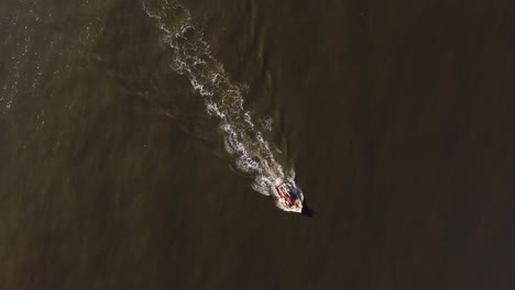 Aerial-top-down-shot-of-fishing-boat-cruising-over-atlantic-ocean-at-sunset