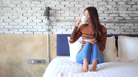 Happy-Young-Woman-Drinking-Morning-Tea-or-Coffee-in-Bed-on-Bright-Morning