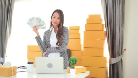 Erfolgreiche-Asiatische-Geschäftsfrau-Im-Büro,-Die-Uns-Dollar-Geldgewinn-In-Der-Hand-Zeigt,-Zeitlupe